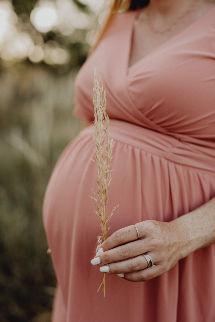 Frau mit Babybauch in rosa Kleid.